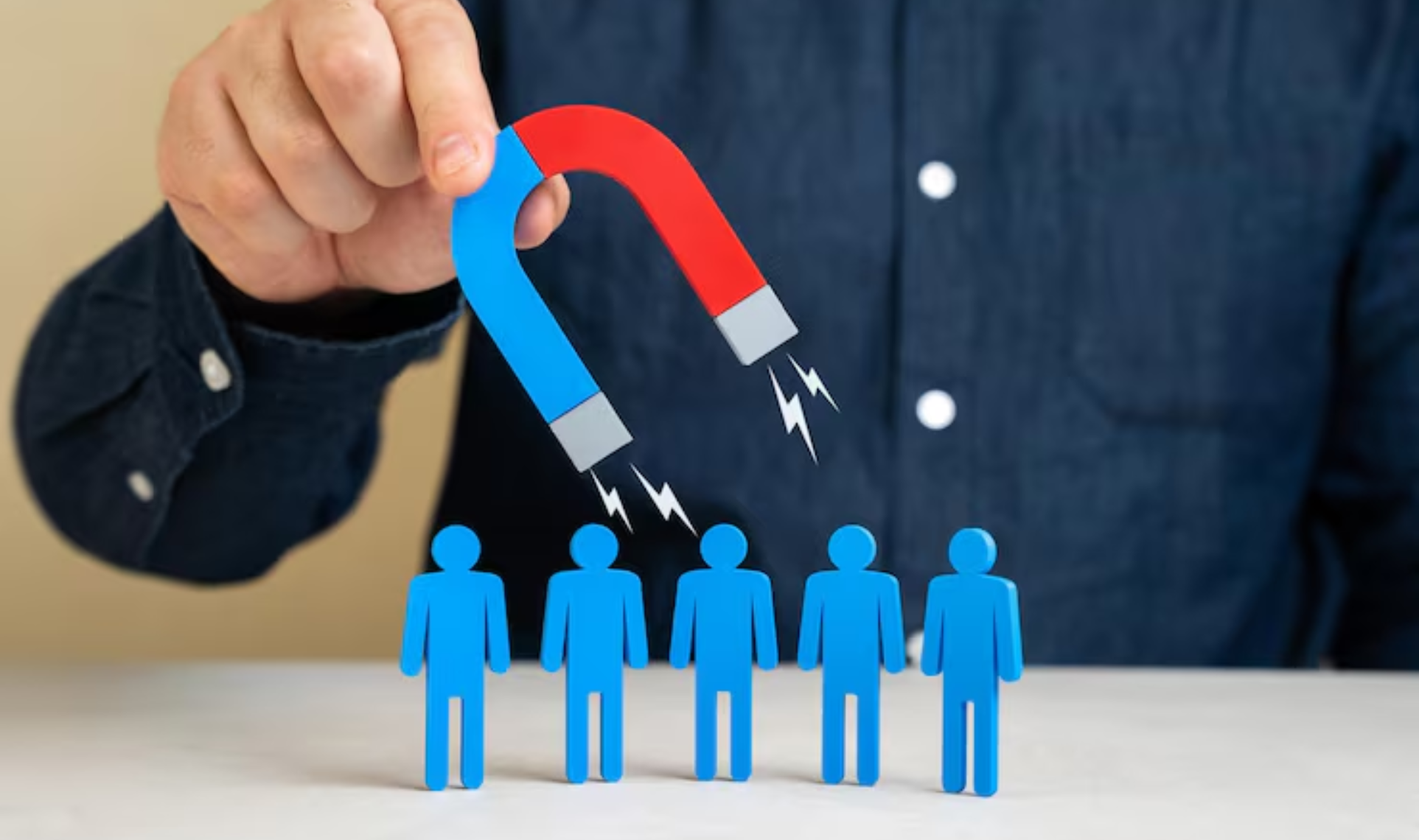 Hand holding a magnet attracting five blue figure icons, symbolizing capturing Consistent Quality Leads.