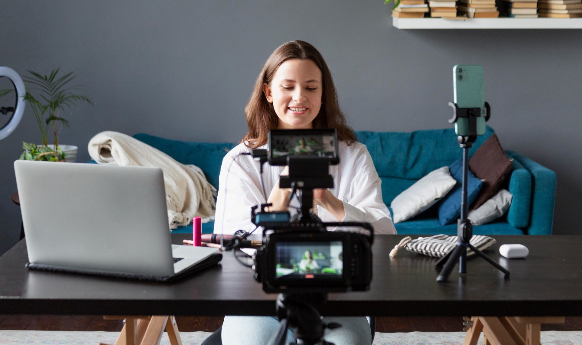 Person recording herself with multiple cameras and a smartphone setup at a desk, creating Video & Multimedia Content.